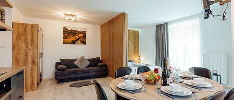 Una sala de estar moderna con comedor, muebles de madera, un sofá y un cuadro en la pared.