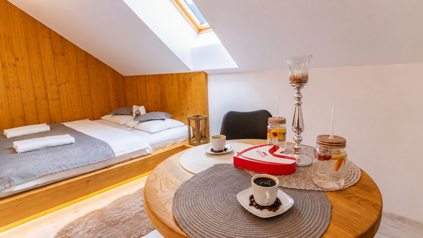 A cozy room with a bed, a round dining table with a cake, and a coffee setup.