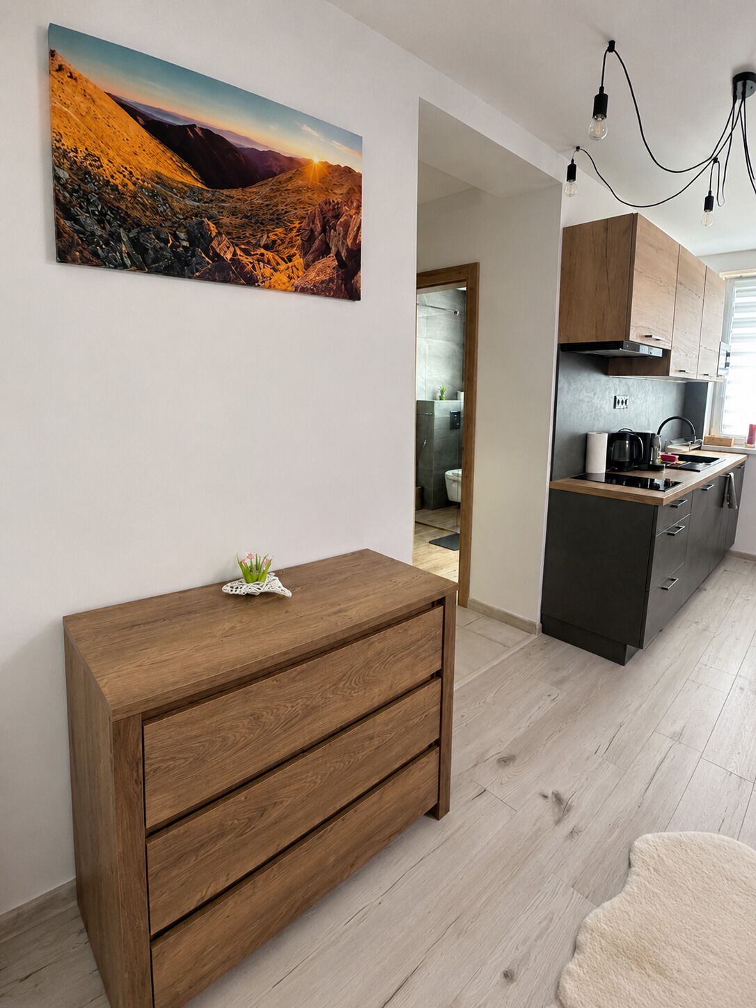 Una cucina moderna con isola integrata, pensili in legno e lampada a sospensione.