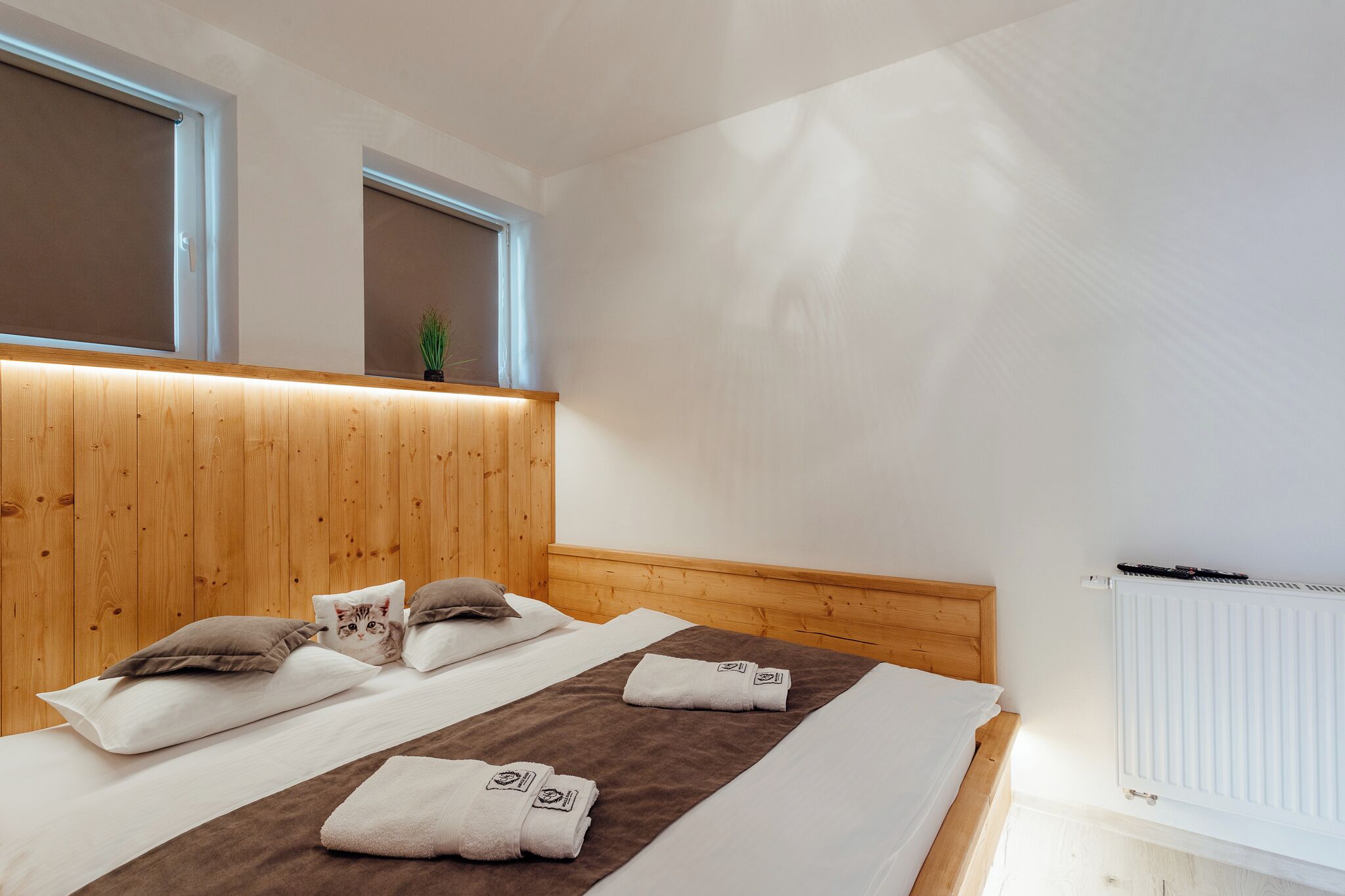 Habitación de hotel con cabecera de madera, dos camas, una ventana con persianas y un radiador.