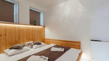 Habitación de hotel con cabecera de madera, dos camas, una ventana con persianas y un radiador.