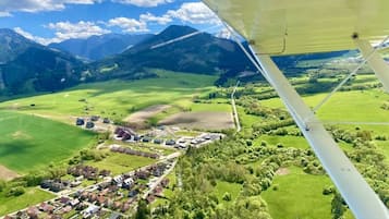 Oversigtsbillede af et landligt landskab med en lille landsby, grønne marker og bjerge i baggrunden.