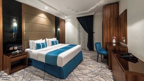 A modern hotel room with a large bed, a desk, and a chair. - Al Qasr Hotel Suites -Al Tahlia District (Khamis Mushait)
