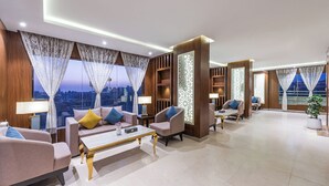 A modern hotel lobby with a sofa set, armchairs, a coffee table, and a decorative partition. - Al Qasr Hotel Suites -Al Tahlia District (Khamis Mushait)