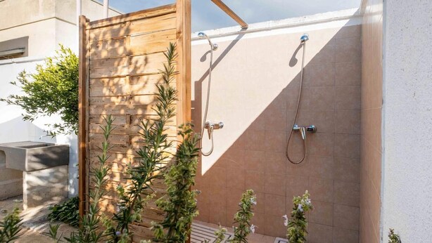 A wooden door leading to a shower area with a tiled wall and a metal showerhead. - Sunny Haven Villa In Torre Lapillo (Porto Cesareo)