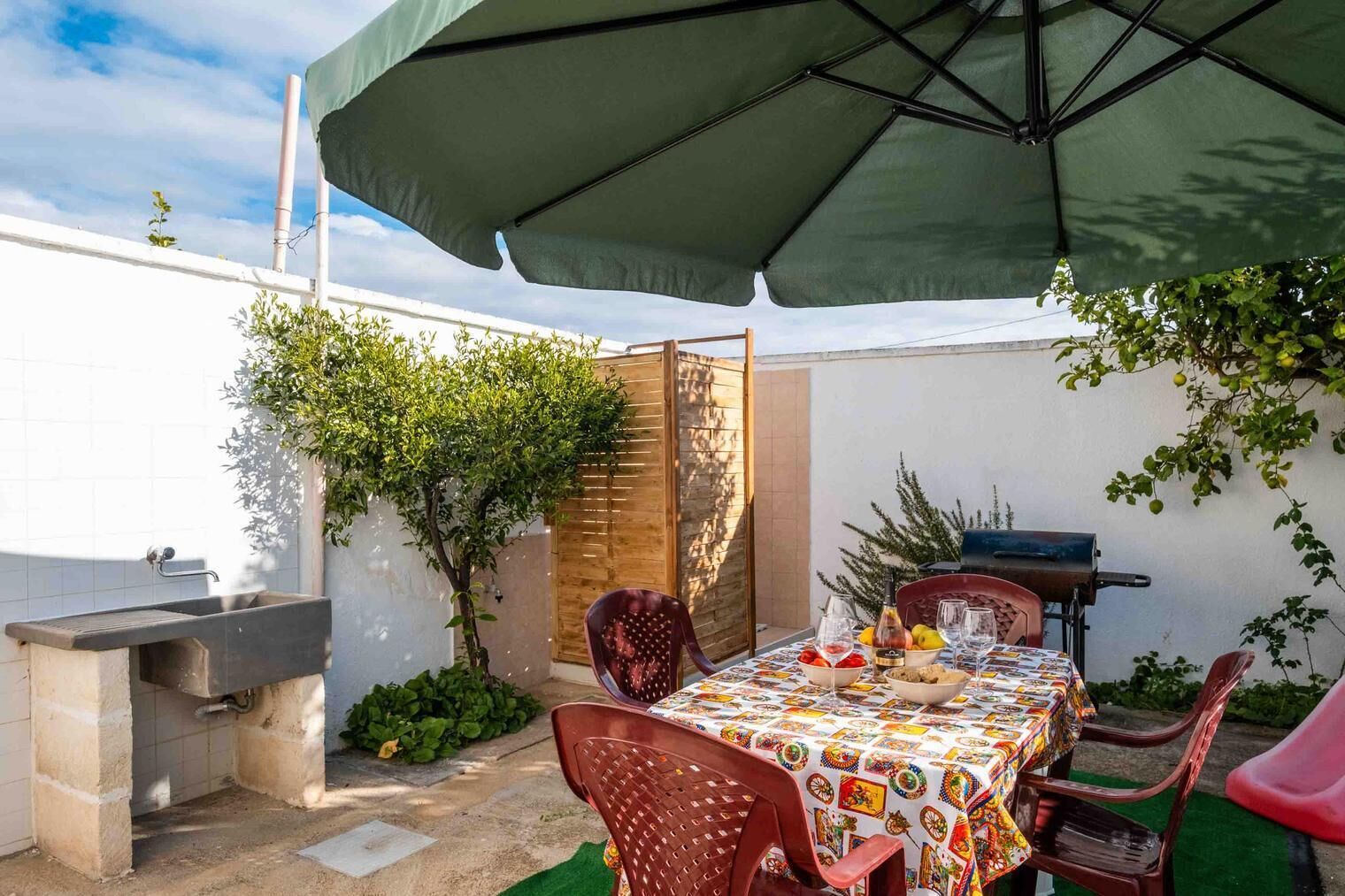 Un patio exterior con mesa lista para comer, una parrilla y un área de estar techada.
