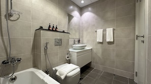 A modern bathroom with a bathtub, a sink with a mirror, and a toilet. - Easygo- STU With High Floor Carson (Dubai)