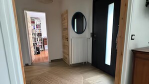 A hallway with a wooden floor, a round mirror on the wall, and a black door. - Near Le Touquet, renovated villa for a relaxing break with family or friends. (Cucq)