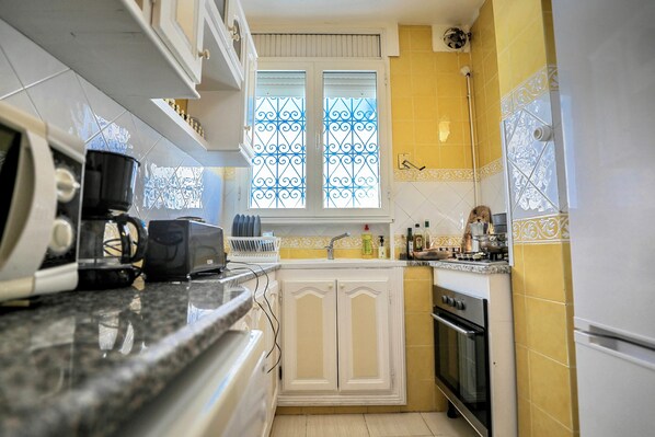 Compact kitchen with oven, sink, and cabinetry, offering ample space for cooking and entertaining.