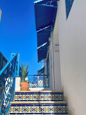 Stairway leading to a charming building with colorful tiles and a blue railing.