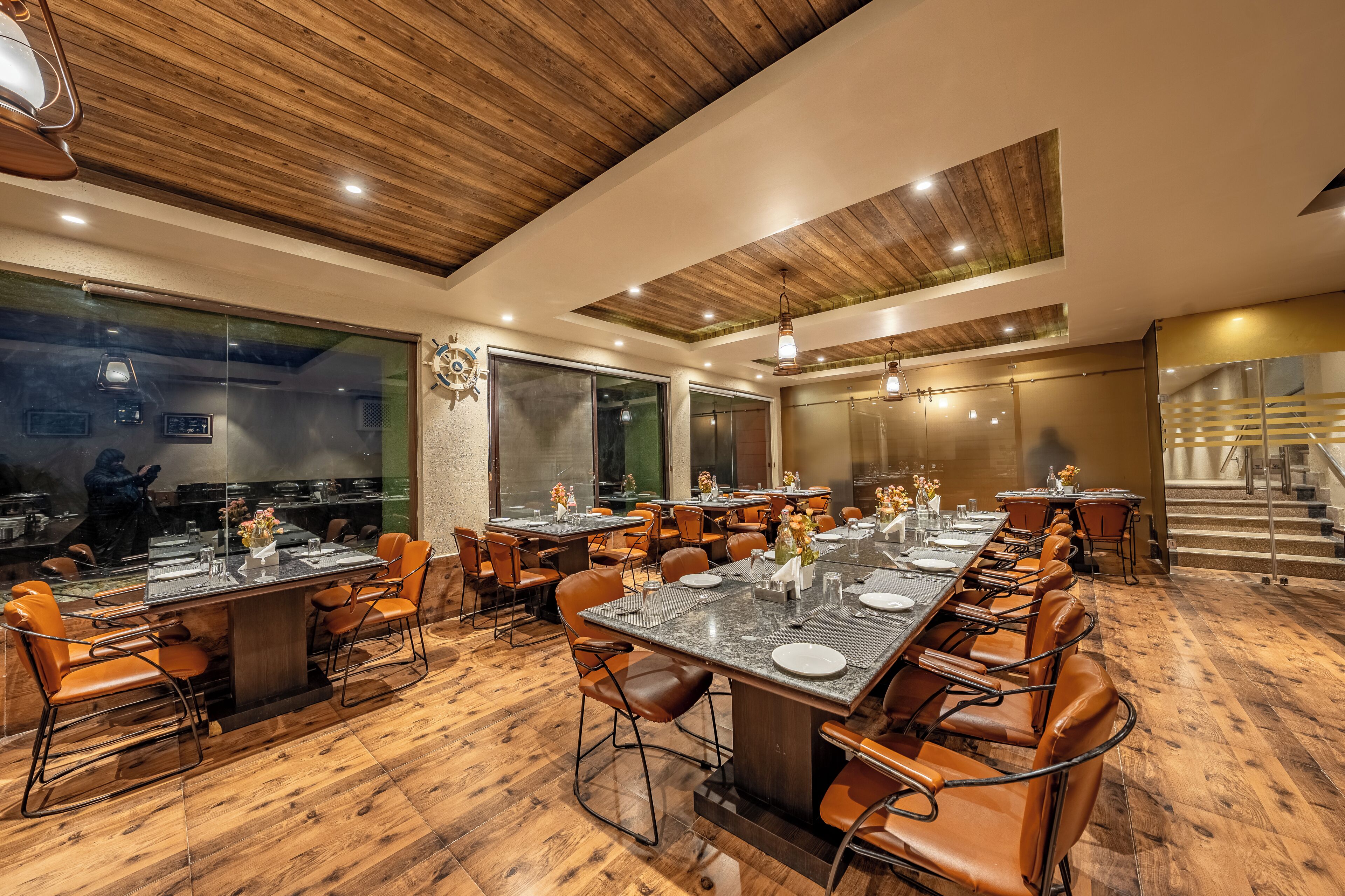 Um restaurante com piso de madeira, várias mesas de jantar e cadeiras de couro.