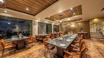 Un restaurante con piso de madera, varias mesas para comer y sillas de cuero.