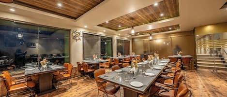 Um restaurante com piso de madeira, várias mesas de jantar e cadeiras de couro.