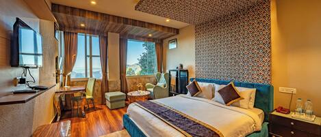 A modern hotel room with a large bed, a desk, and a view of the mountains.