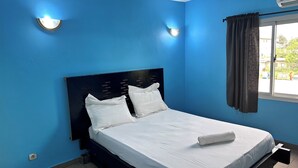 Een hotelkamer met een enkel bed, witte beddengoed en een donkerblauwe wand.