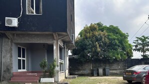 Een gebouw met twee verdiepingen, een donkere gevel, een zichtbare airconditioning en een klein voortrek met treden.