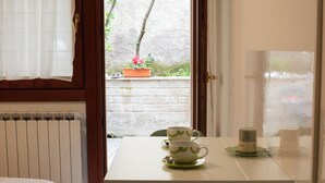 Ein Zimmer mit einem Bett, einem Tisch mit zwei Tassen und einem Untertasse sowie Blick auf einen Garten.