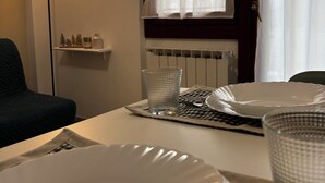 Ein Essbereich mit einem Tisch für zwei Personen, einer Lampe und einem fenster mit Vorhängen.