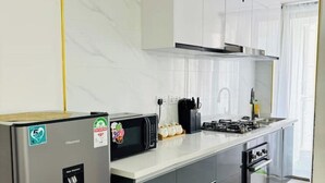 A modern kitchen with a refrigerator, microwave, stove, and sink. - Cosy apartment in KILIMANI 
Mini golf 
restaurant 
Smrt TV
parking 
gym
security (Nairobi)