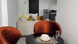 A modern room with a bed, a dining table with chairs, a refrigerator, and a microwave. - Cosy apartment in KILIMANI 
Mini golf 
restaurant 
Smrt TV
parking 
gym
security (Nairobi)