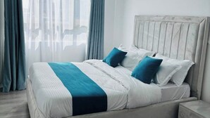 A neatly made bed with a striped bedspread, a headboard, and two pillows. - Cosy apartment in KILIMANI 
Mini golf 
restaurant 
Smrt TV
parking 
gym
security (Nairobi)