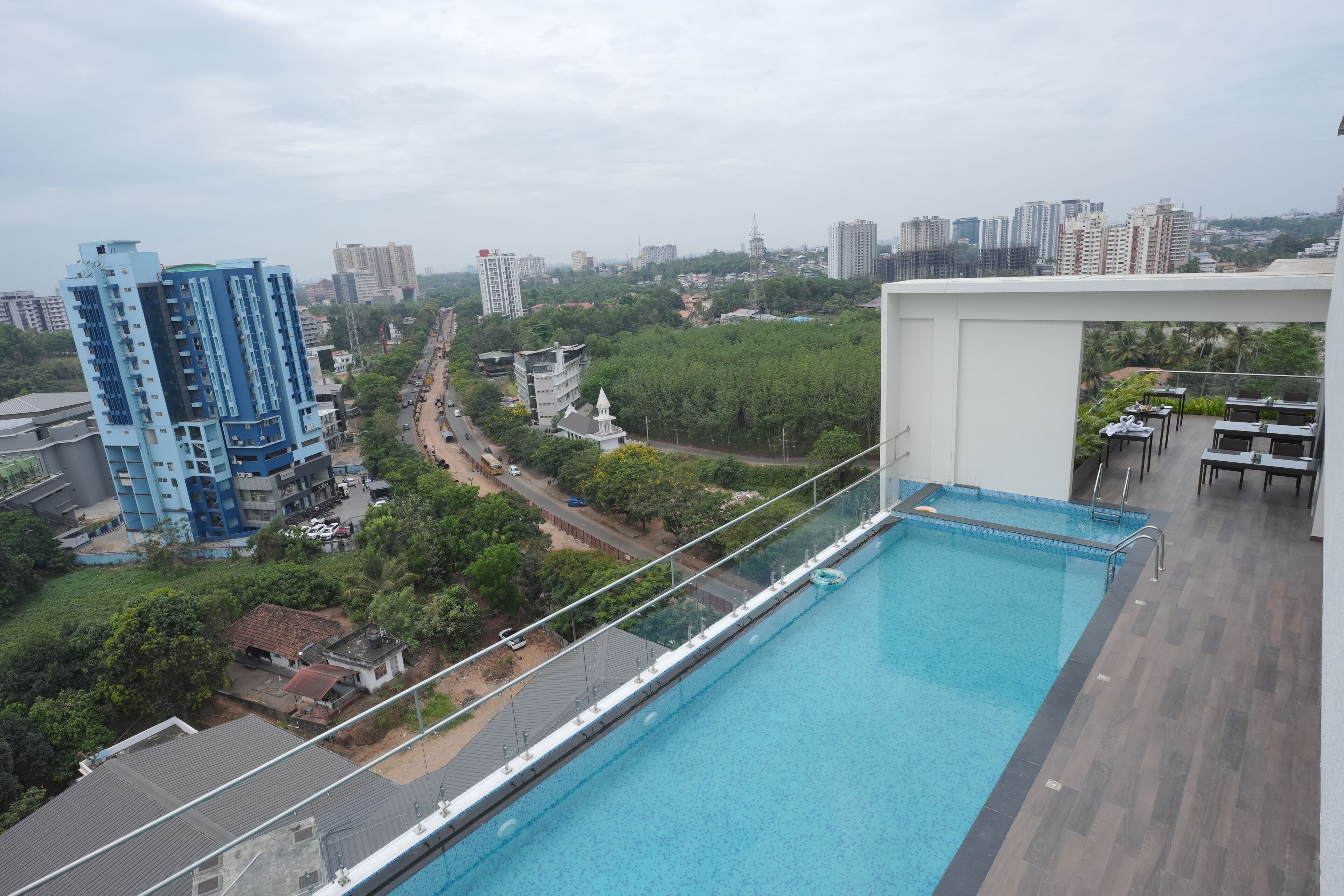Una piscina en la azotea con vistas a un paisaje urbano, que incluye edificios altos y áreas verdes.