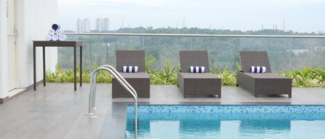 A pool area with lounge chairs and a small table with towels.