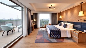 A modern hotel room with a large bed, bedside tables, a desk, and a balcony with seating. - Clarion Hotel Khayal Kochi, Infopark (Kanayannur)