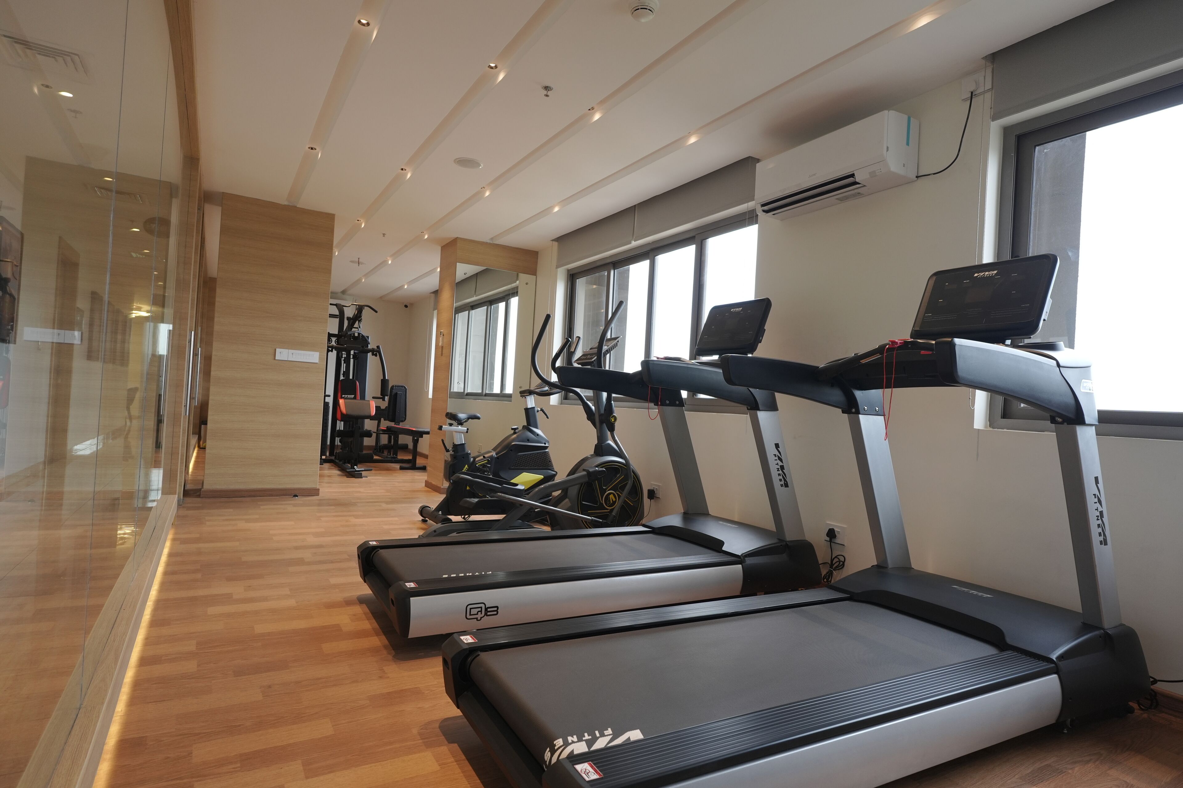 Een fitnessruimte met loopbanden, hometrainers en een roeimachine.
