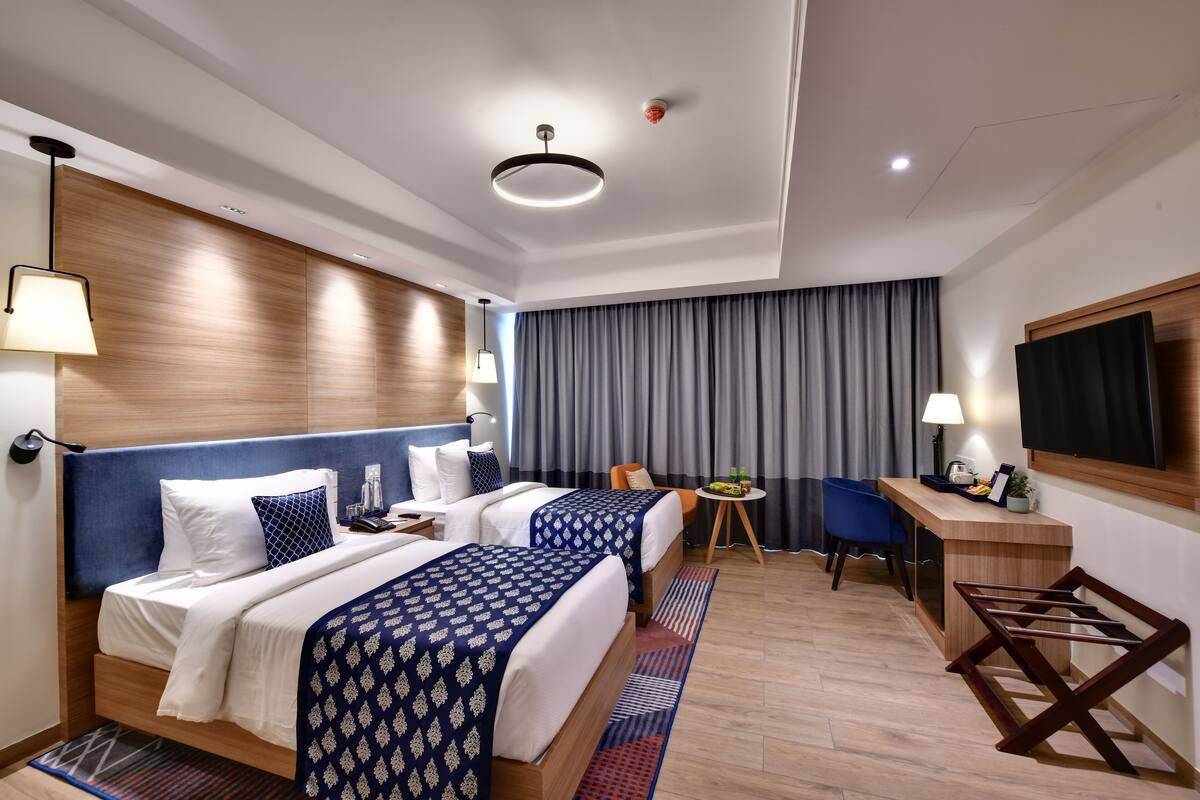 Een moderne hotelkamer met twee bedden, een bureau, een stoel en een televisie.