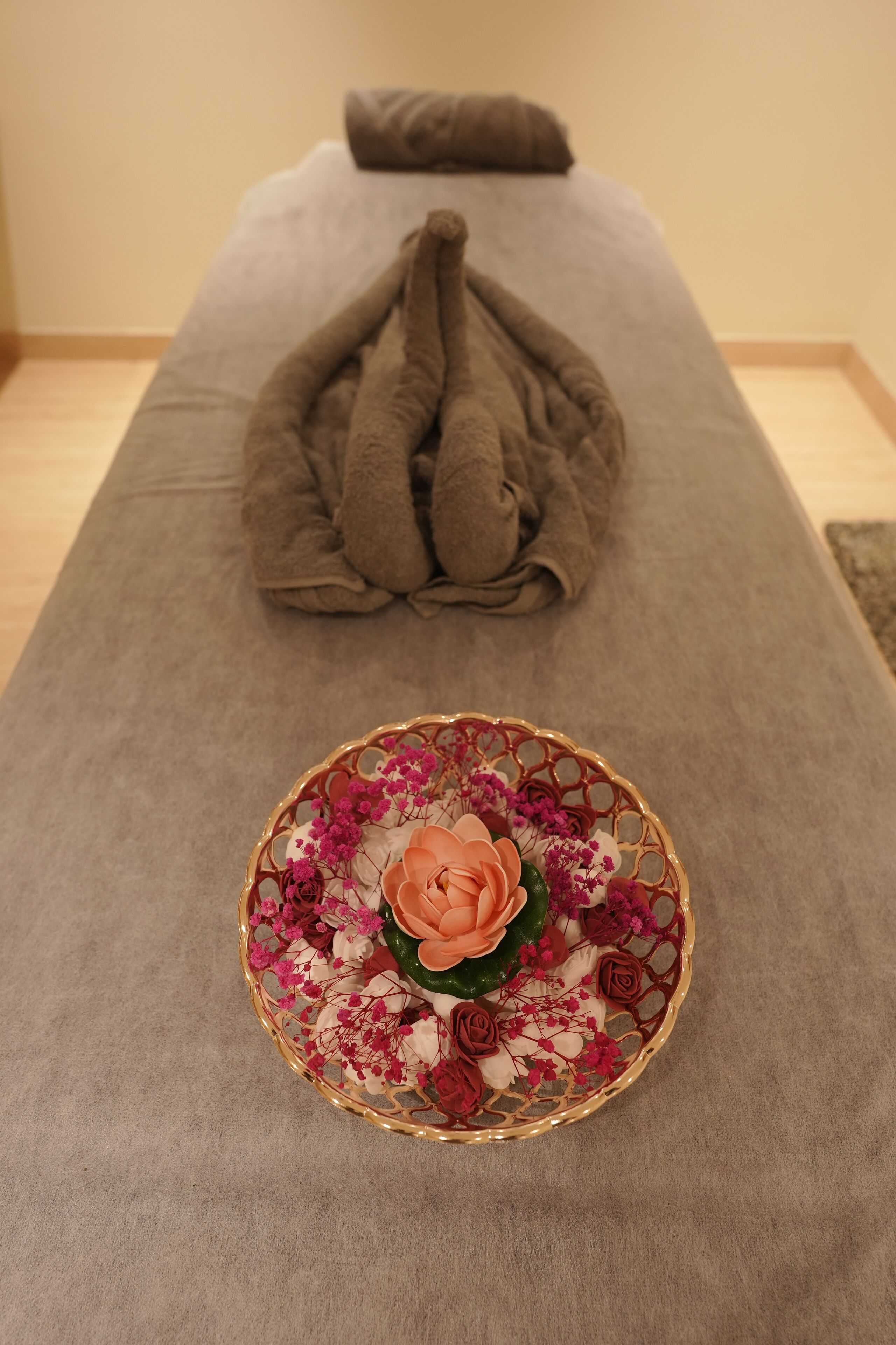 Una mesa para masajes con una toalla y un plato decorativo con flores.