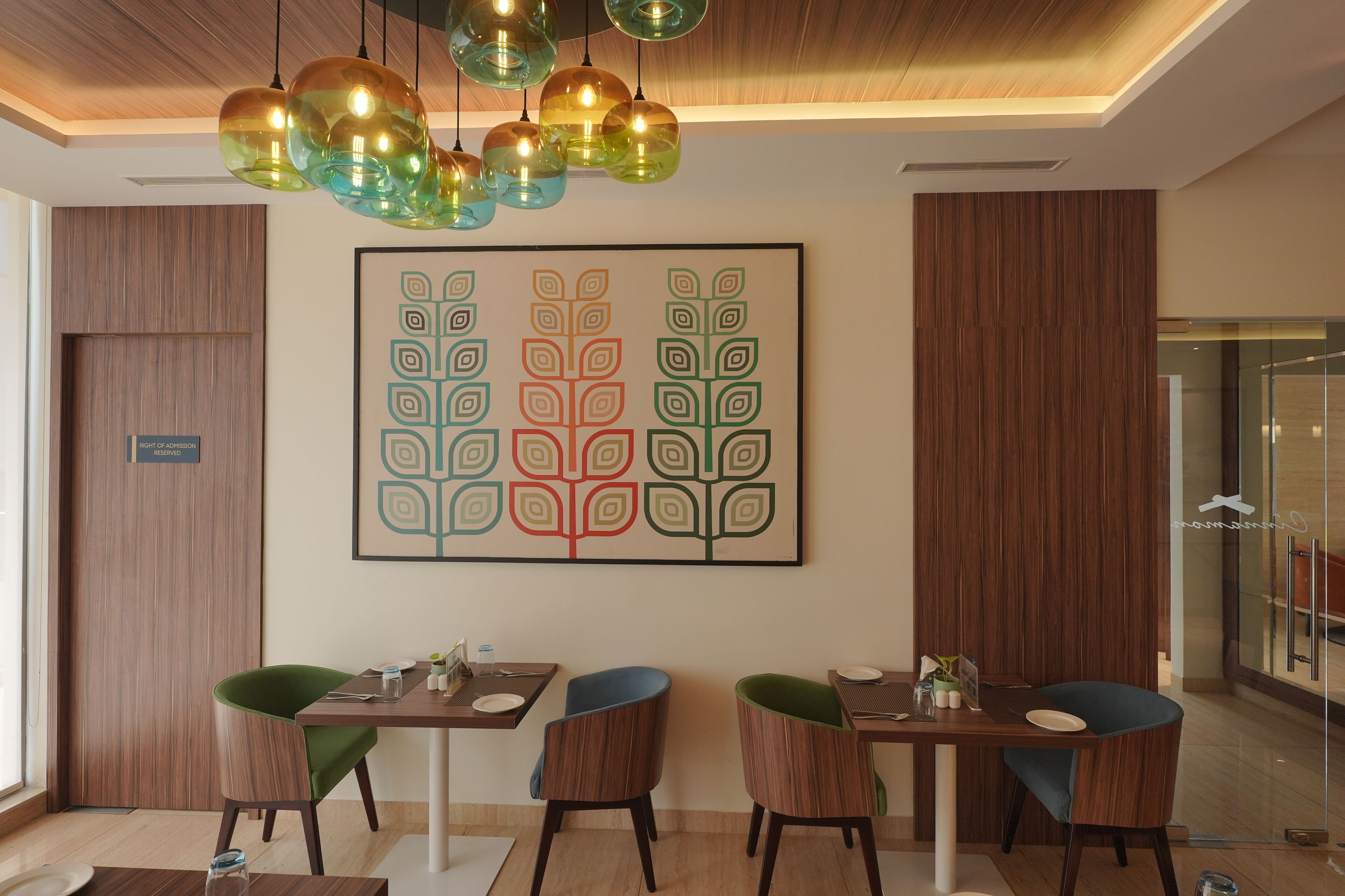 A modern dining area with a wooden ceiling, a large abstract painting, and two tables with chairs.