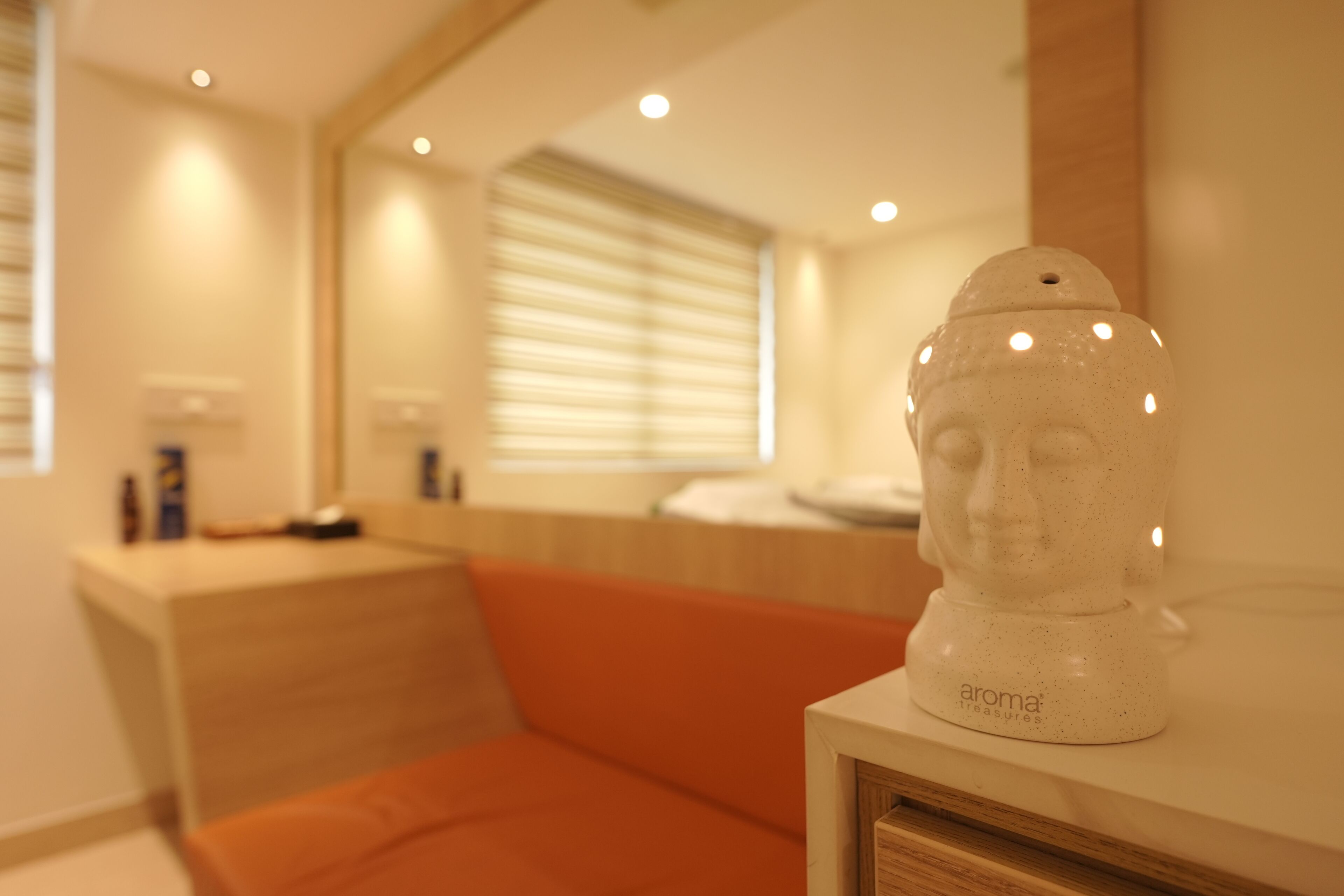 A modern bathroom with a wooden vanity, a white ceramic sculpture, and a window with blinds.