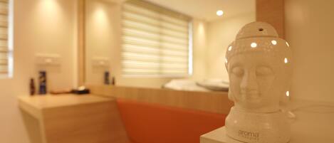 A modern bathroom with a wooden vanity, a white ceramic sculpture, and a window with blinds.