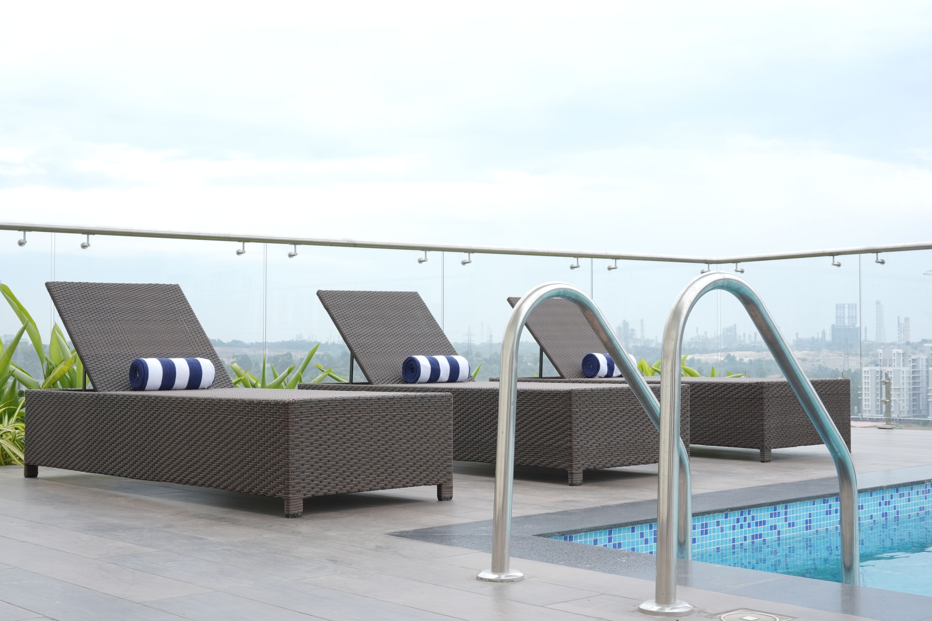 Zona de piscina en la azotea con sillas de descanso y barandilla junto a la piscina.