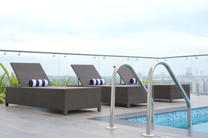 Zona de piscina en la azotea con sillas de descanso y barandilla junto a la piscina.
