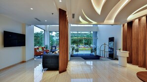 A modern lobby with a large TV, seating area, and a view of the outside. - Clarion Hotel Khayal Kochi, Infopark (Kanayannur)