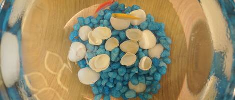 A bowl filled with blue and white pebbles and a few fish.