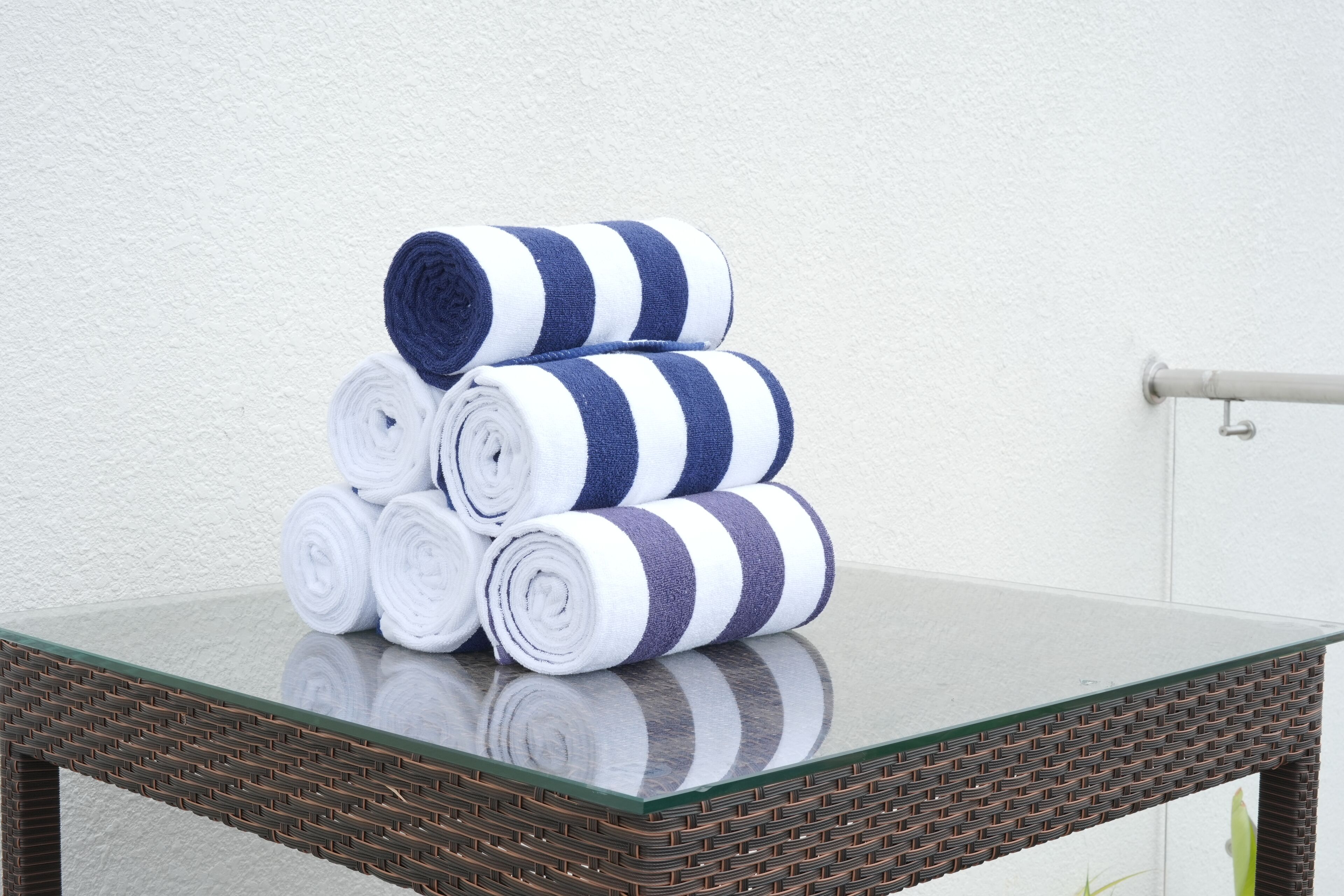 A stack of striped towels on a glass table against a white wall.