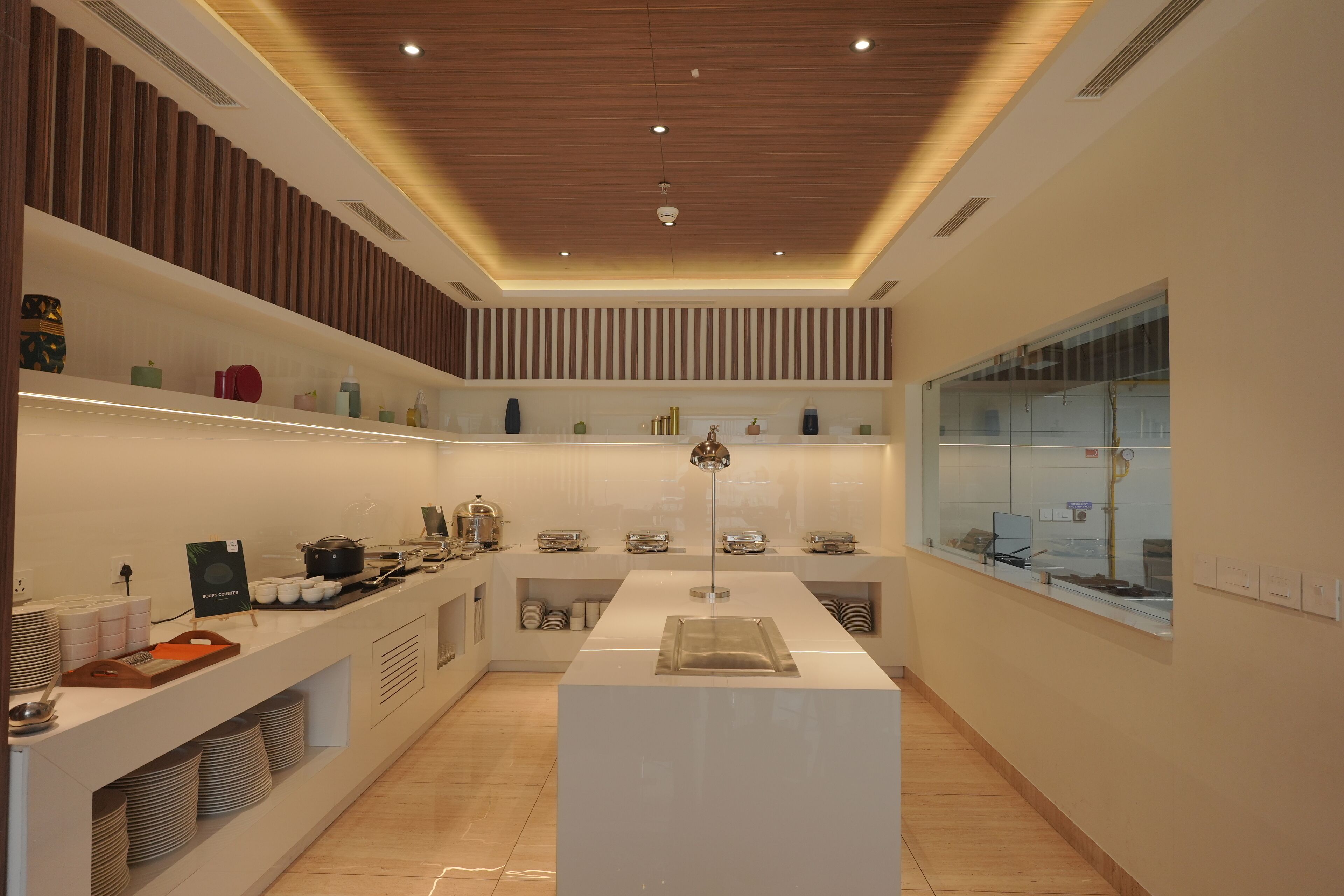 A modern kitchen with a central island, built-in shelves, and a large window.