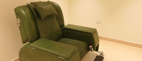 A massage chair with a footrest and a small white side table with a phone.