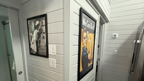 Een gang met twee ingelijste posters aan de wanden, een deur en een trap.