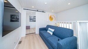 A modern living room with a blue sofa, a flat-screen TV, and artwork on the walls. - Bubbles and Brews, Premium Views at Roadrunner Resort (Parker)