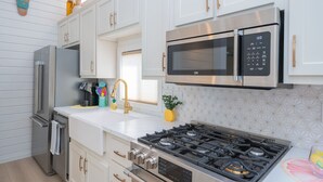A modern kitchen with white cabinetry, stainless steel appliances, a gas stove, and a microwave. - Bubbles and Brews, Premium Views at Roadrunner Resort (Parker)
