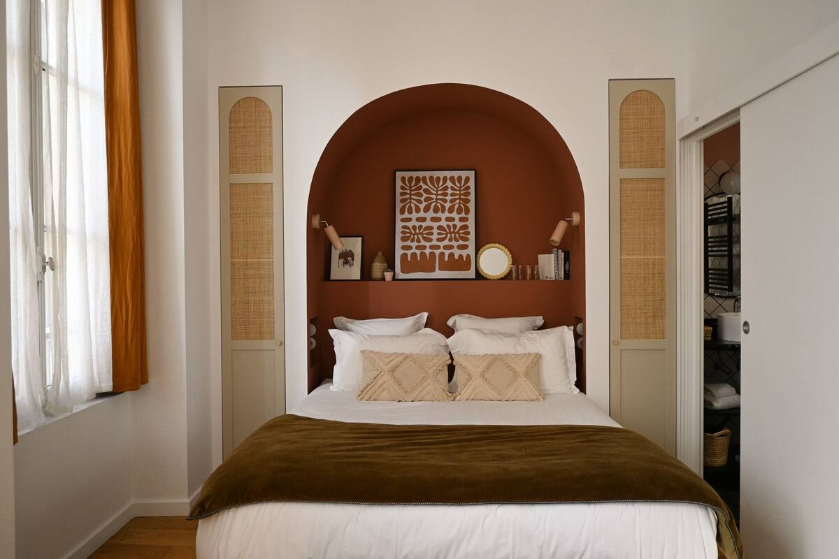 Quarto com uma cama grande, cabeceira marrom e um objeto decorativo acima da cama.