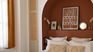 Une chambre à coucher comprenant un lit, des oreillers, un miroir fixé au mur et un panneau décoratif.