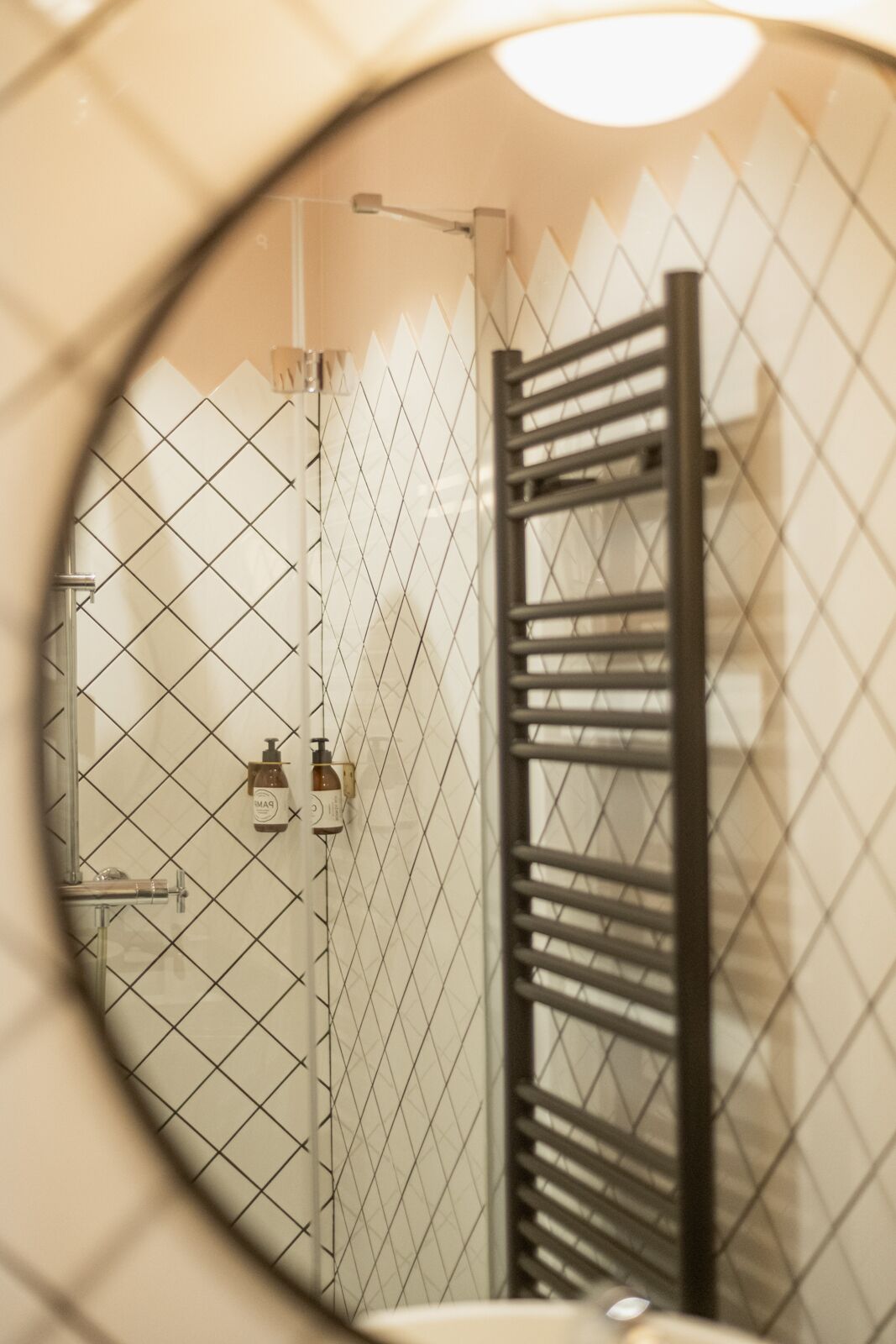 Un baño con pared de azulejos, un perchero y una zona de ducha.