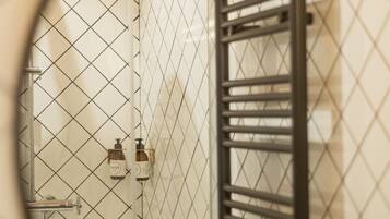 Un baño con pared de azulejos, un perchero y una zona de ducha.