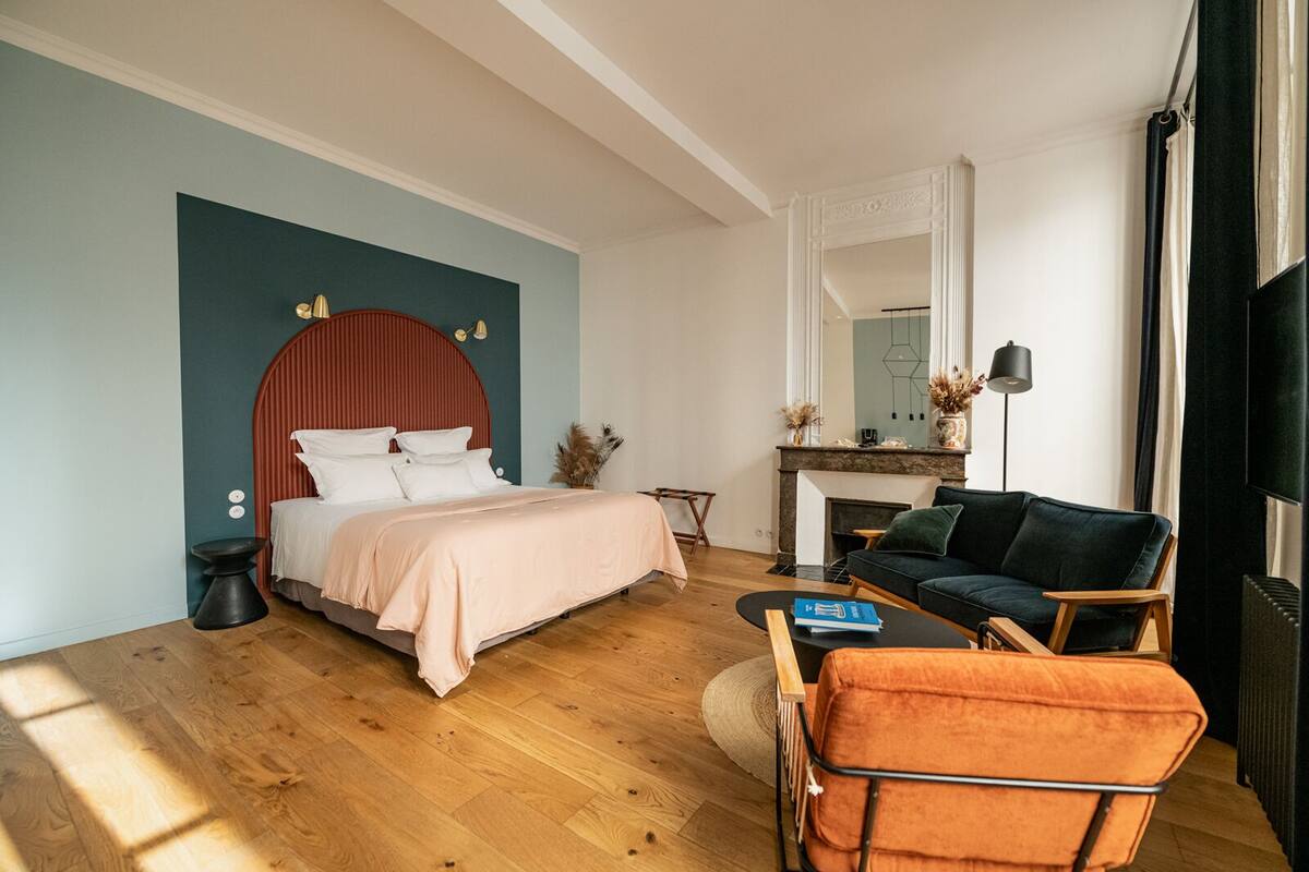 Quarto moderno com cama, sofá, mesa de centro e lareira.