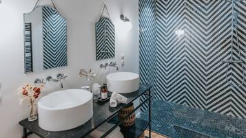A modern bathroom with two sinks, a mirror, and a shower.